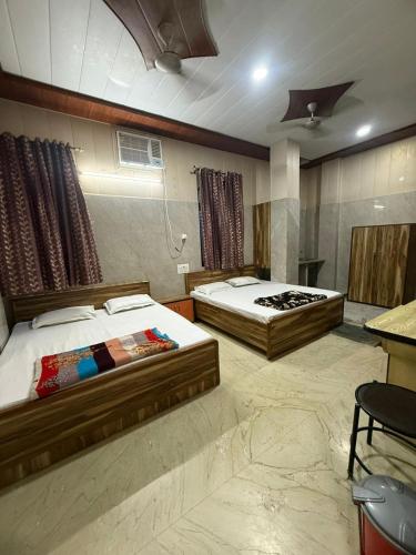 a bedroom with two beds and a table in it at Kalindi Blessings Deluxe Guest House in Mathura