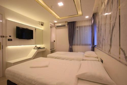 a hotel room with two beds and a flat screen tv at Pratunam Atrium Hotel in Bangkok