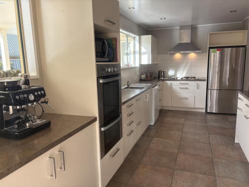 a kitchen with white cabinets and a black appliance at Alpine Rose Retreat in Arrowtown