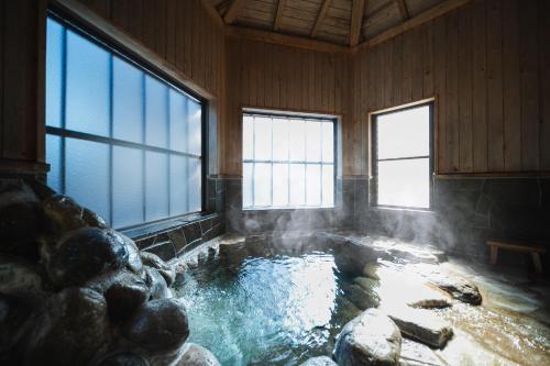 a pool of water in a room with windows at Beppu RIN in Beppu