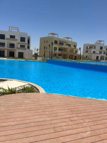 a large blue swimming pool with buildings in the background at One B2b Apartment w balcony with Jacuzzi at Makadi Heights in Hurghada