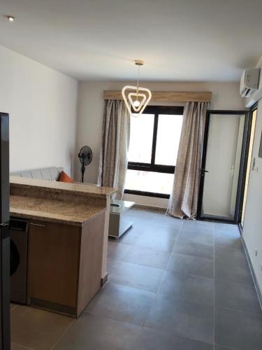 a living room with a kitchen and a large window at One B2b Apartment w balcony with Jacuzzi at Makadi Heights in Hurghada