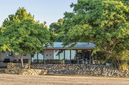a house with a stone wall and two trees at Petra Olive 1 in Yallingup