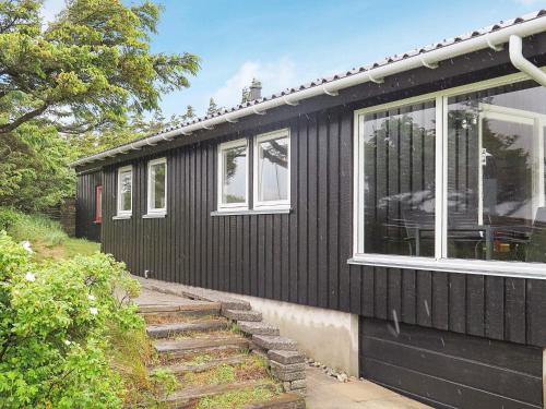 a black house with white windows and stairs in front at 7 person holiday home in Struer-By Traum in Remmer Strand