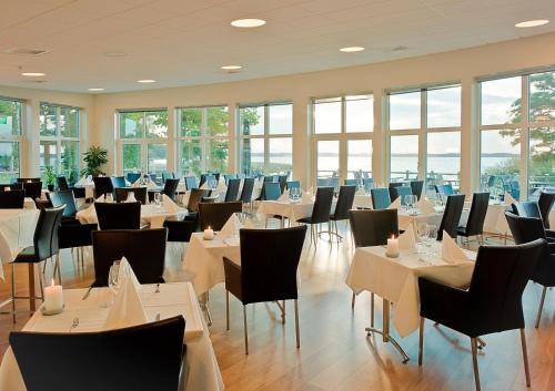 un comedor con mesas, sillas y ventanas en Ringsjöstrand Hotel, en Hörby