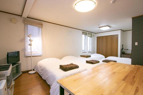 a room with two beds and a table and a television at Hello house / Vacation STAY 2248 in Sapporo
