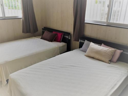 two beds in a small room with windows at Nago - House / Vacation STAY 76289 in Nago