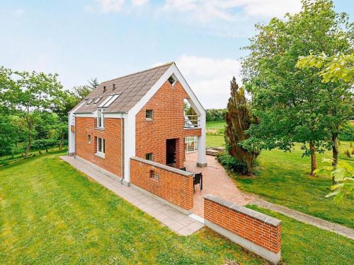 a brick house in a field with a grass yard at Luxury Retreat with Pool - By Traum Ferienwohnungen in Hvalpsund