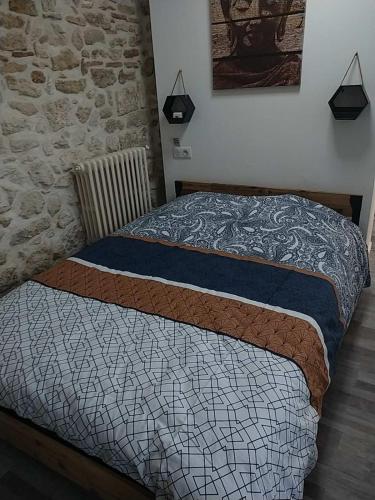 ein Bett in einem Schlafzimmer mit einer Steinmauer in der Unterkunft Studio T2 Montfrin Pont du Gard in Montfrin
