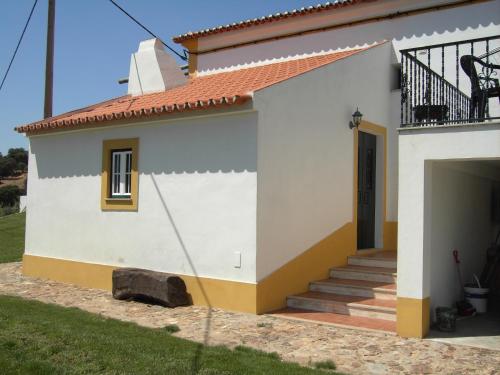 a white house with a staircase and a balcony at Farmhouse in Montemor near Évora in Montemor-o-Novo