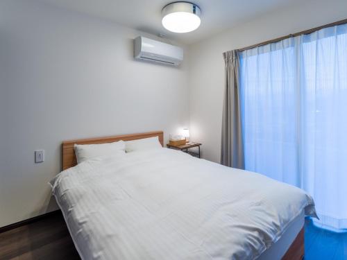 ein Schlafzimmer mit einem großen weißen Bett mit einem Fenster in der Unterkunft Rakuten STAY HOUSE x WILL STYLE Sasebo 103 in Sasebo