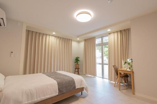 a bedroom with a bed and a desk and a window at 栞-shiori-FUNAKURA in Ishigaki Island