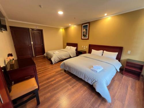 a hotel room with two beds and a desk at Hotel California by Chat Noir in Cuenca