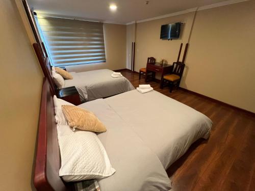 a hotel room with two beds and a desk at Hotel California by Chat Noir in Cuenca