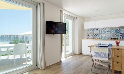 a kitchen with a tv on the wall and a table at Le Palme Village in Terracina