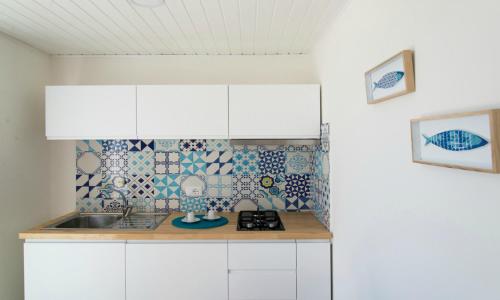 a kitchen with white cabinets and blue and white tiles at Le Palme Village in Terracina
