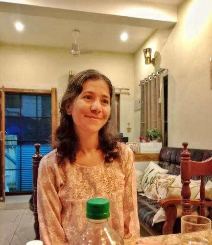 a woman sitting at a table with a water bottle at Guestland Homestay in Cochin