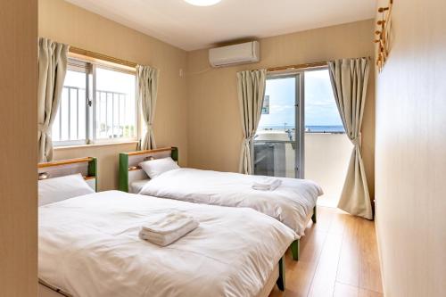 two beds in a room with a view of the ocean at The villas Machidooya / Vacation STAY 35629 in Motobu