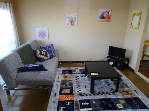 a living room with a couch and a table at Merbeil Otsuka / Vacation STAY 4984 in Nikaidō