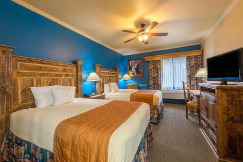 a hotel room with two beds and a flat screen tv at La Hacienda Inn near Alamodome & Riverwalk in San Antonio
