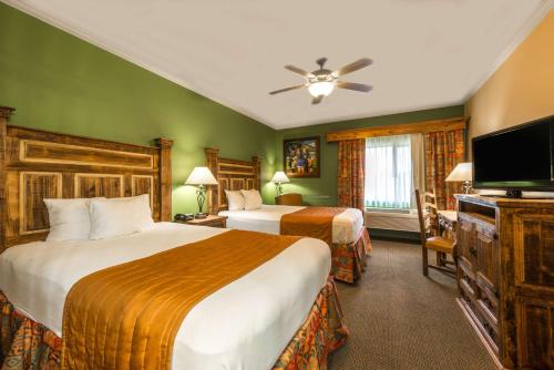 a hotel room with two beds and a flat screen tv at La Hacienda Inn near Alamodome & Riverwalk in San Antonio