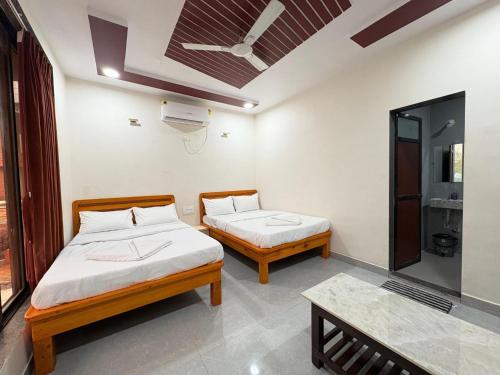 a room with two beds and a table at Sandalwoods Resort in Neral