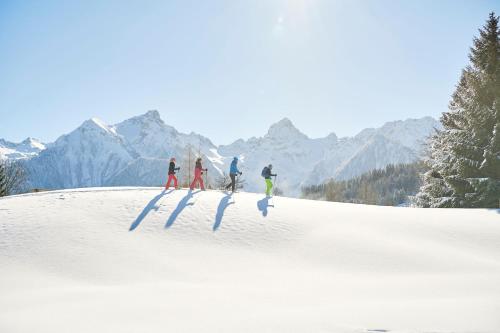a group of four people skiing down a snow covered slope at Appartementhaus Studa 29 in Brand