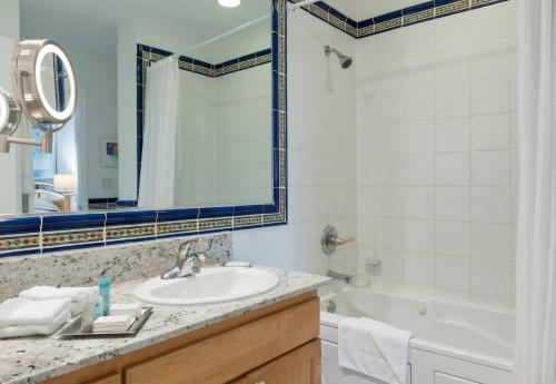 ein Badezimmer mit einem Waschbecken, einer Badewanne und einem Spiegel in der Unterkunft Wyndham Reef Resort, Grand Cayman in Sand Bluff