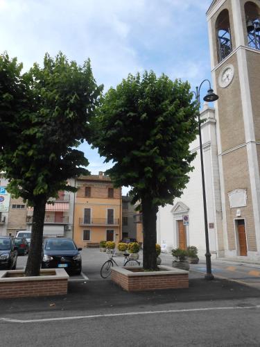 three trees in a parking lot in front of a clock tower at Lo Spedalicchio in Bastia Umbra