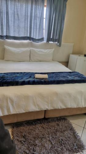 a bed with a blue blanket and pillows on it at Fide Guest House Mthatha in Mthatha