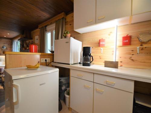 a kitchen with white cabinets and a white refrigerator at Cozy Chalet with barbecue in Trou du Diable