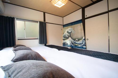 a room with three beds and a painting on the wall at Omori Tei大森亭OMT 18min to Haneda, 3min Omori, Max 7 people in Tokyo