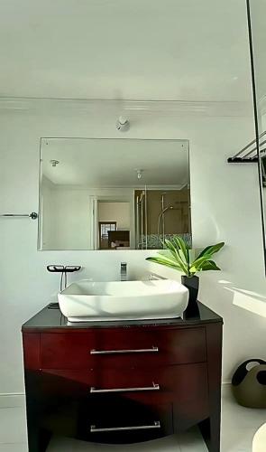 a bathroom with a sink and a large mirror at Sunset Serenity 2BR Oceanview Beach & Pool Access 