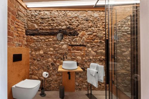 a bathroom with a stone wall with a toilet and a sink at Decanter House in Borgomanero