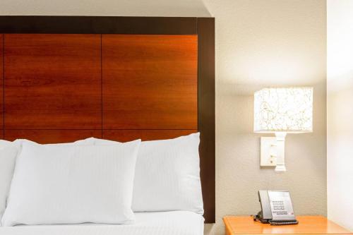 a bed with a wooden headboard and a phone on a table at La Quinta by Wyndham San Antonio Airport in San Antonio