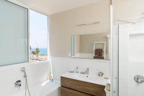 ネタニヤにあるLuxury 3BR with Sea Views in Netanya By Barnesの浴槽、洗面台、鏡のあるバスルーム