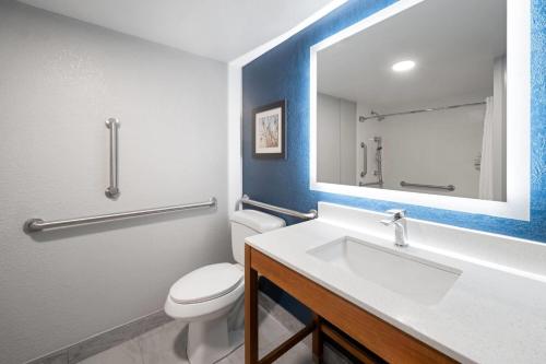 a bathroom with a toilet and a sink with a mirror at La Quinta by Wyndham Raleigh Cary in Cary