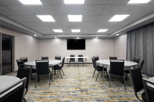 a conference room with tables and chairs and a screen at La Quinta by Wyndham Raleigh Cary in Cary