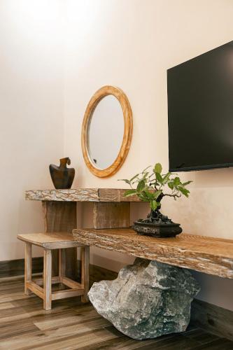 a room with a tv and a rock and a mirror at Palm Garden Beach Resort & Spa in Hoi An