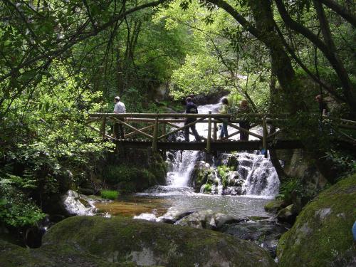 people walking over a bridge over a waterfall at Douro Hotel Porto Antigo in Cinfães