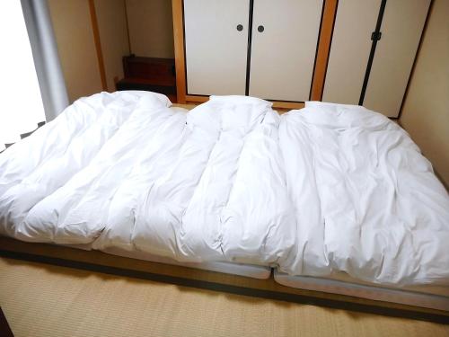 a bed with white sheets on it in a room at Bhome Hikone Jizo in Hikone