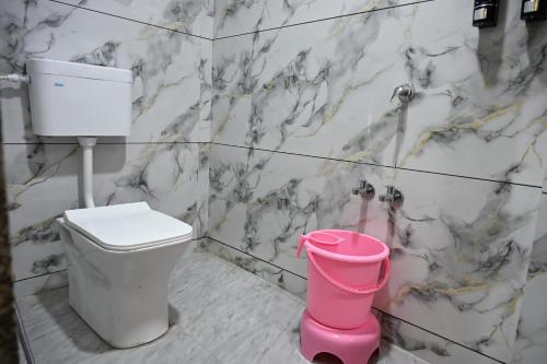 a bathroom with a toilet and a pink bucket at Hotel Ravechi Krupa in Kotharia