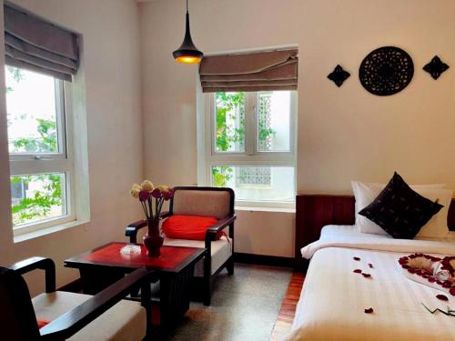 a room with two beds and a table and a chair at Indra Angkor Residence in Siem Reap