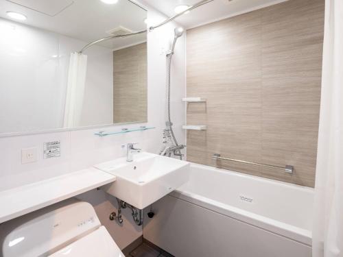 a white bathroom with a sink and a mirror at Comfort Hotel Takamatsu in Takamatsu