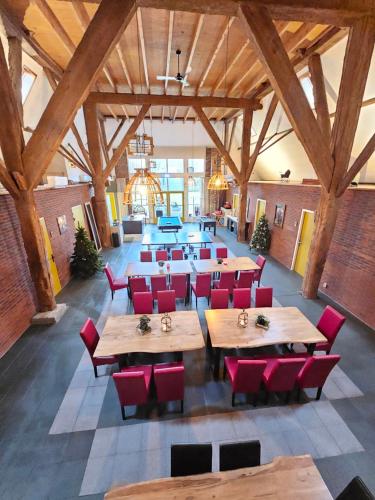 a restaurant with wooden tables and red chairs at Vakantiehuis Kleastermar met 12 slaapkamers in Oostermeer