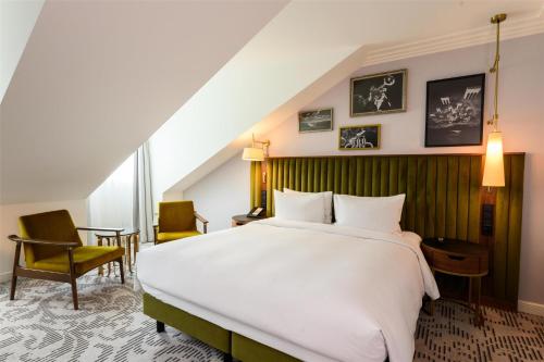a bedroom with a large white bed and chairs at Hotel Saski Krakow Curio Collection by Hilton in Kraków