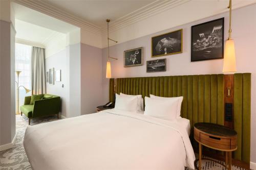 a bedroom with a large white bed and a green wall at Hotel Saski Krakow Curio Collection by Hilton in Kraków