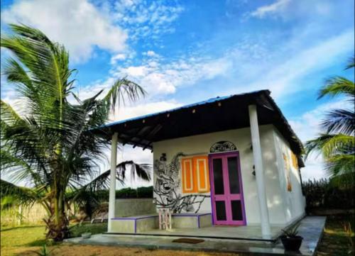 a small house with a pink door and palm trees at Coco Cabana Kite Resort Kalpitiya in Kalpitiya