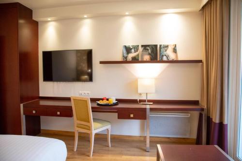 a hotel room with a desk and a television at Clarion Paris CDG Airport in Roissy-en-France