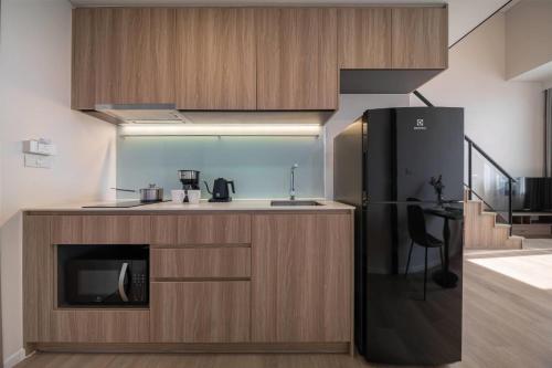 a kitchen with a black refrigerator and a sink at Ramada By Wyndham Bangkok Sukhumvit 87 in Bangkok